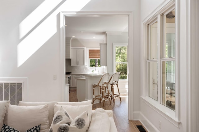 interior space featuring crown molding, light wood-type flooring, visible vents, and recessed lighting