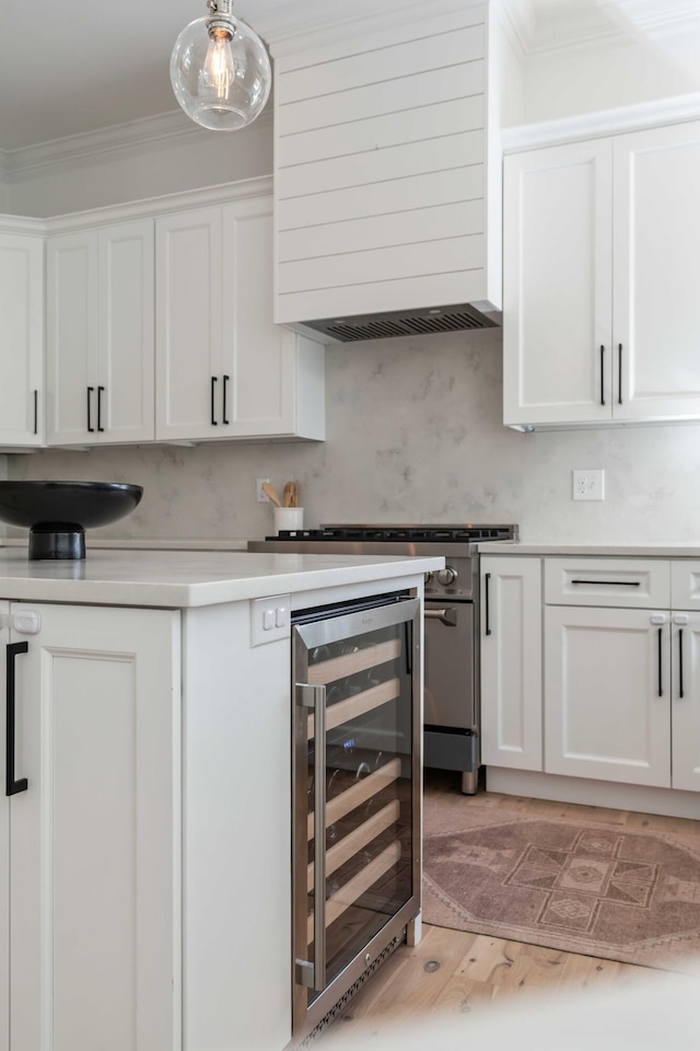 kitchen with crown molding, custom exhaust hood, white cabinetry, light countertops, and beverage cooler