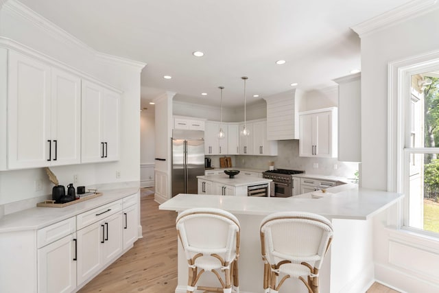 kitchen featuring a breakfast bar, white cabinetry, light countertops, high end appliances, and light wood-style floors