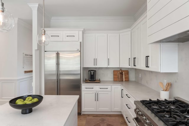 kitchen featuring stainless steel built in refrigerator, stove, custom range hood, white cabinetry, and light countertops