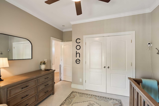 bedroom featuring light colored carpet, ornamental molding, a closet, and ceiling fan