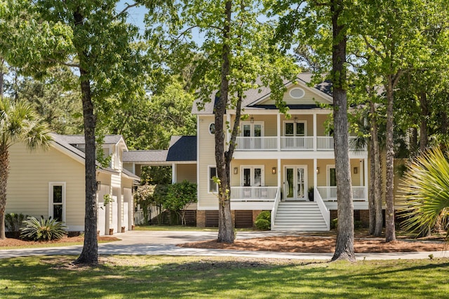 greek revival inspired property featuring a balcony, french doors, covered porch, stairs, and concrete driveway
