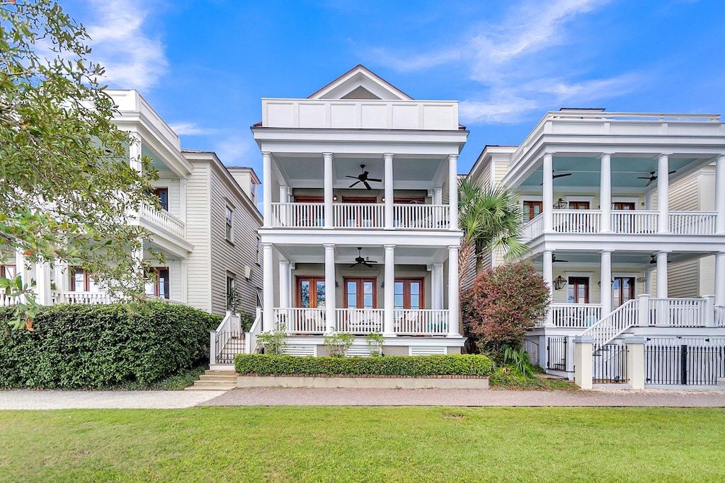 coastal inspired home featuring a balcony, a porch, ceiling fan, and a front yard