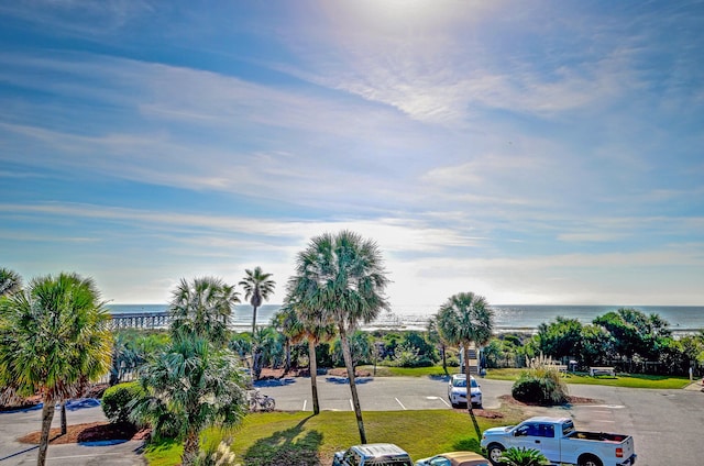 exterior space featuring uncovered parking, a water view, and a lawn