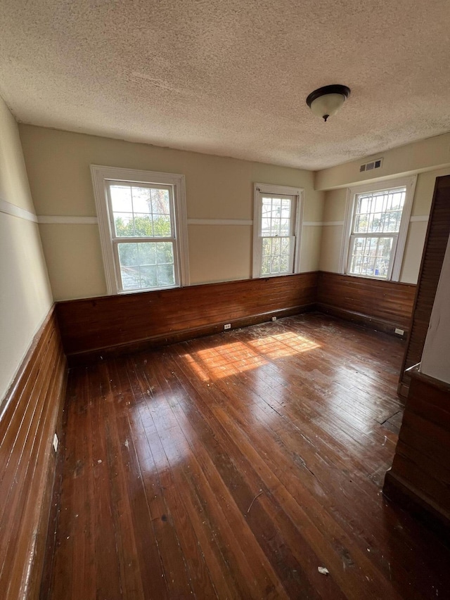 unfurnished room with a textured ceiling and dark wood-type flooring