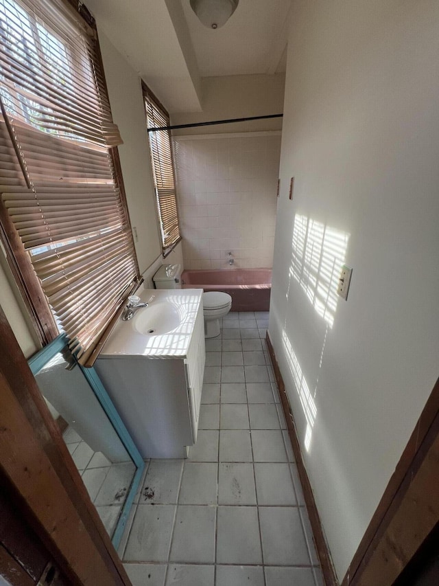 bathroom with tile patterned floors, a tub to relax in, vanity, and toilet