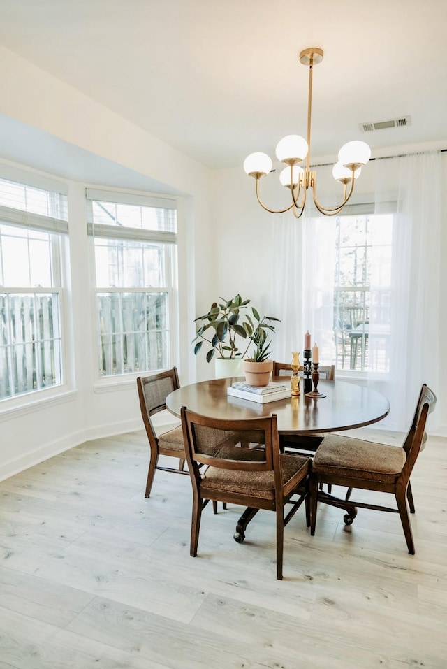 dining area featuring visible vents, baseboards, light wood-style flooring, and an inviting chandelier