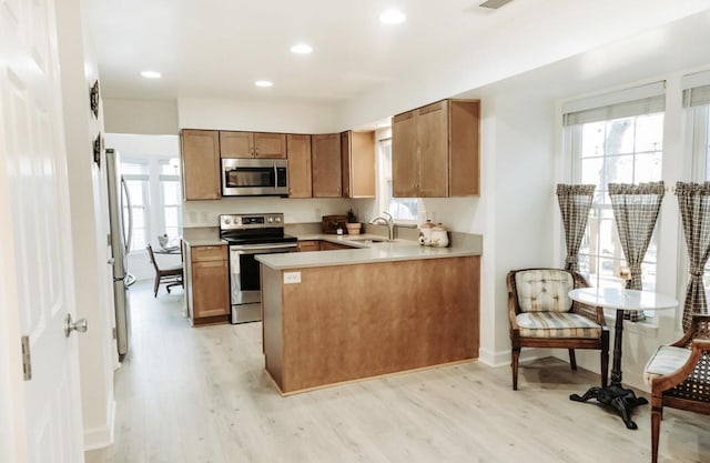 kitchen featuring a peninsula, brown cabinets, stainless steel appliances, and light countertops