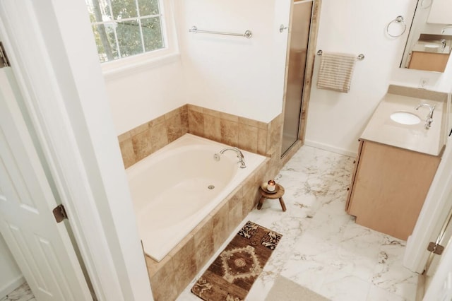 full bath featuring marble finish floor, a garden tub, vanity, and baseboards