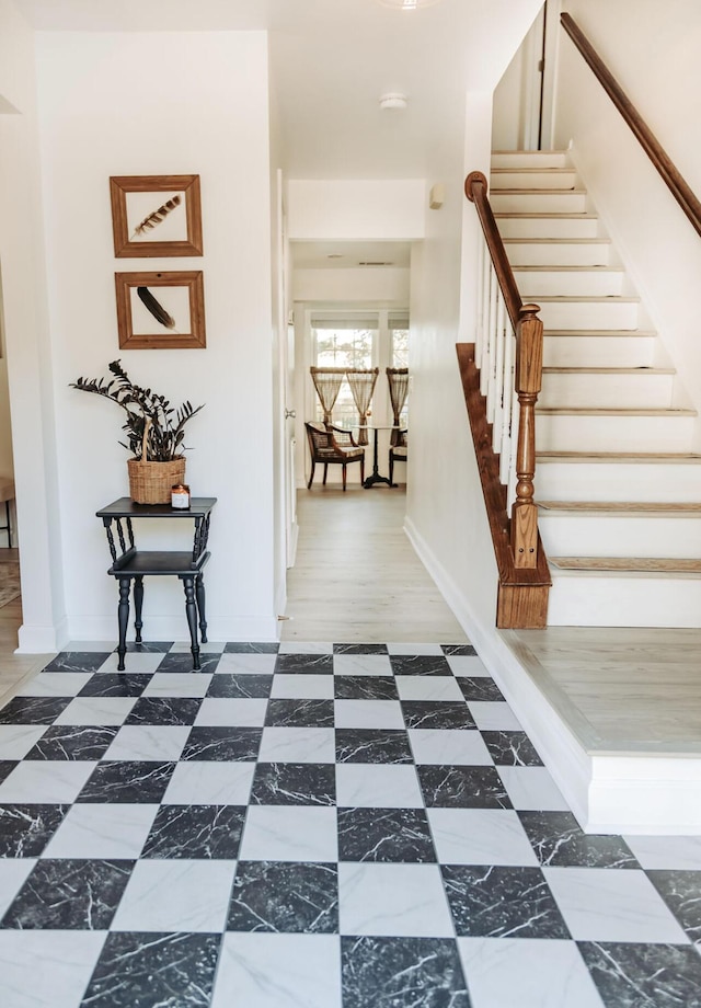 corridor with dark floors, stairway, and baseboards