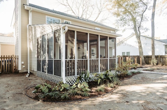 view of property exterior with a sunroom, fence, and a chimney