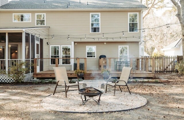 rear view of property featuring an outdoor fire pit, a sunroom, and a deck