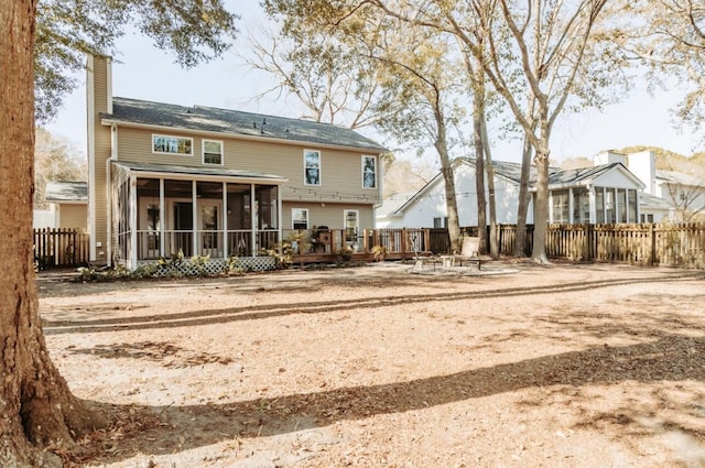 back of property with a fire pit, fence, a sunroom, a wooden deck, and a chimney