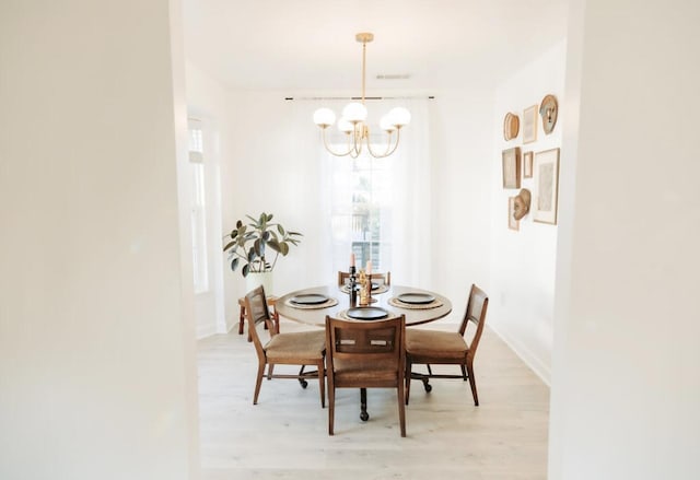 dining area featuring a chandelier, light wood-type flooring, and baseboards