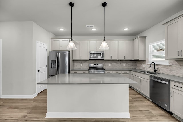 4308 Cotton Flt Rd, Summerville, SC 29485 - kitchen featuring appliances with stainless steel finishes, a sink, light wood finished floors, a center island, and decorative backsplash