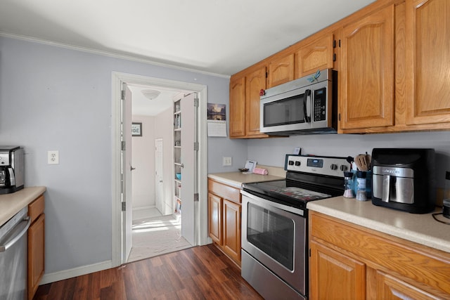 kitchen featuring dark hardwood / wood-style flooring, ornamental molding, and appliances with stainless steel finishes