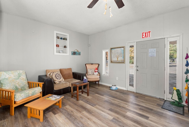 living area featuring built in shelves, ceiling fan, a textured ceiling, and hardwood / wood-style flooring