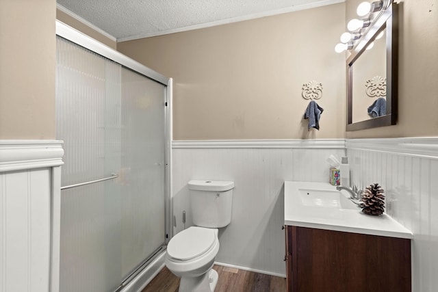 bathroom with vanity, a textured ceiling, crown molding, wood-type flooring, and toilet