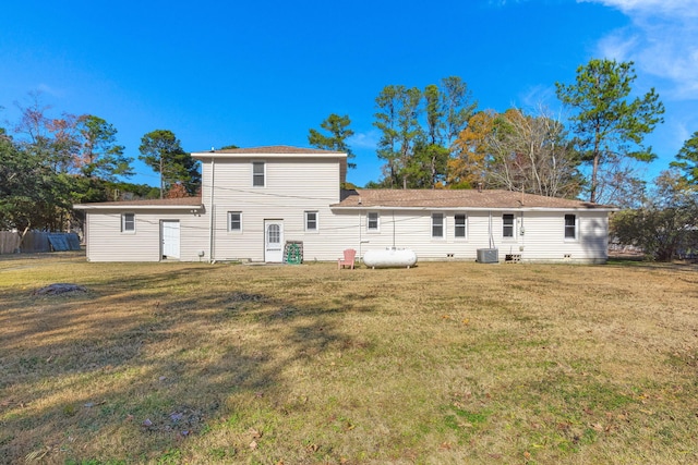 rear view of house featuring central AC and a lawn