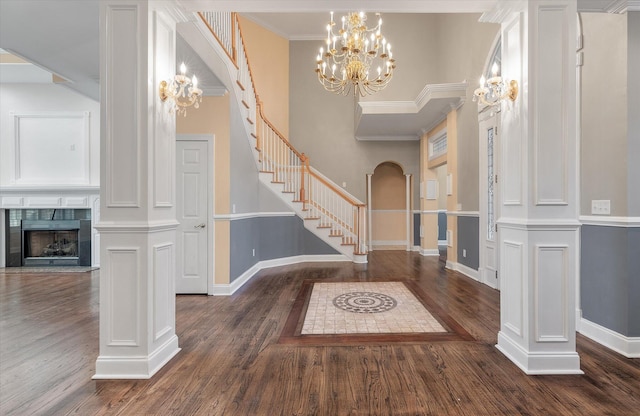 entryway with an inviting chandelier, dark hardwood / wood-style floors, ornamental molding, and a tile fireplace