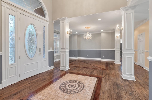 entrance foyer with crown molding, dark hardwood / wood-style flooring, decorative columns, and a notable chandelier