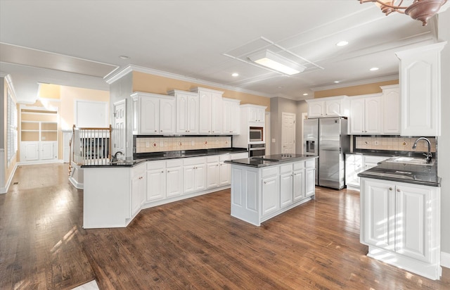 kitchen featuring appliances with stainless steel finishes, dark hardwood / wood-style floors, white cabinetry, sink, and a center island