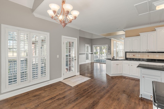 kitchen with pendant lighting, crown molding, dark wood-type flooring, tasteful backsplash, and white cabinets