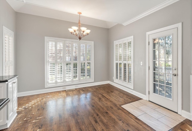 unfurnished dining area featuring hardwood / wood-style flooring, ornamental molding, and a notable chandelier