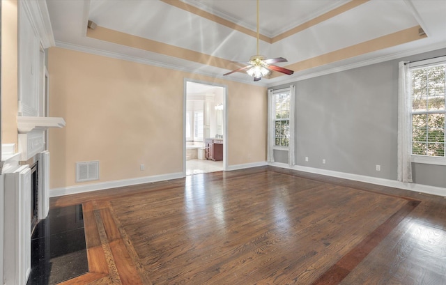 unfurnished living room featuring dark hardwood / wood-style floors, ornamental molding, and a raised ceiling