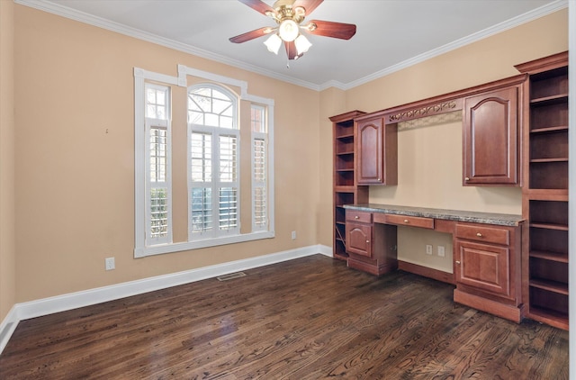 unfurnished office featuring crown molding, ceiling fan, built in desk, and dark wood-type flooring