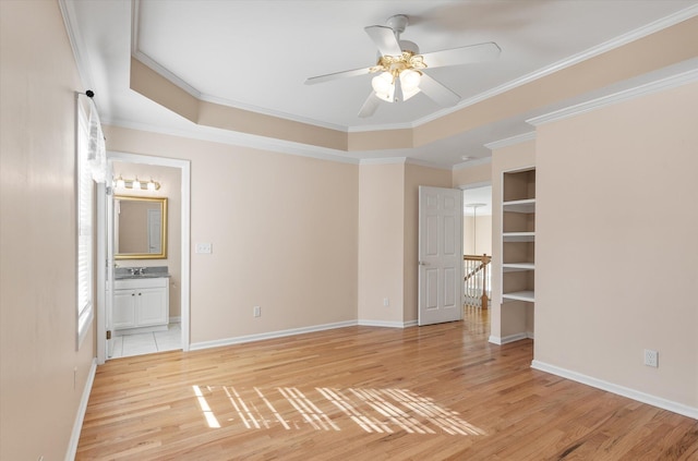 unfurnished bedroom featuring ensuite bath, ornamental molding, a raised ceiling, and ceiling fan