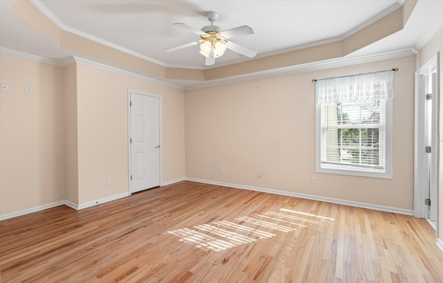 spare room with ceiling fan, ornamental molding, a tray ceiling, and light hardwood / wood-style flooring