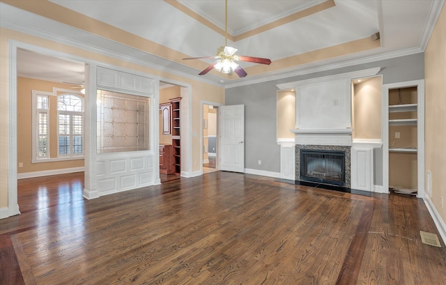 unfurnished living room featuring crown molding, dark hardwood / wood-style floors, a tray ceiling, ceiling fan, and a premium fireplace