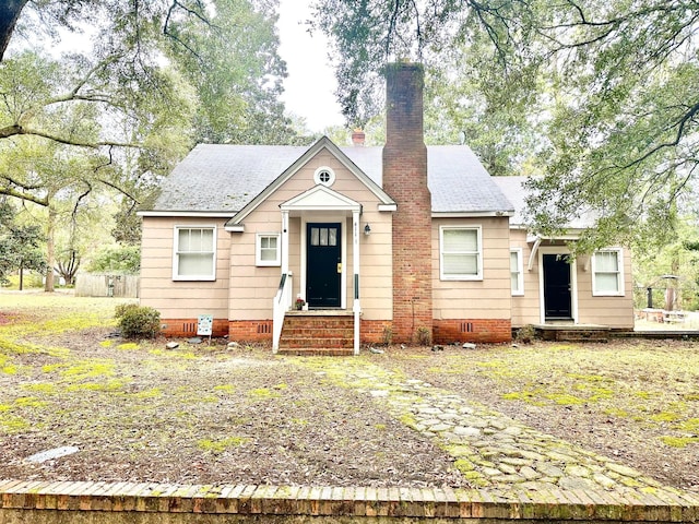 bungalow-style home featuring entry steps, a shingled roof, crawl space, and a chimney