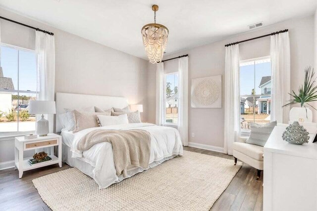 bedroom with multiple windows, dark wood-type flooring, and a notable chandelier