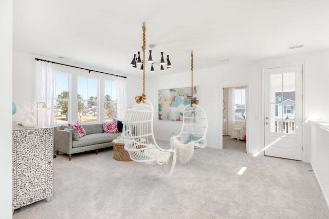 carpeted living room featuring a wealth of natural light and an inviting chandelier