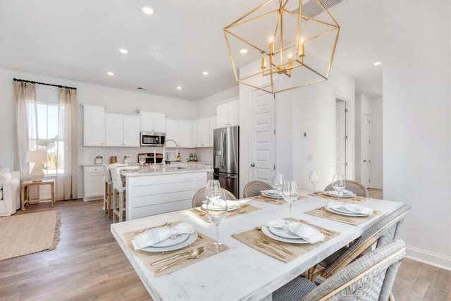 dining space with a notable chandelier, light hardwood / wood-style floors, and sink