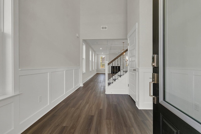 foyer entrance with dark wood-style flooring, visible vents, a decorative wall, and stairs