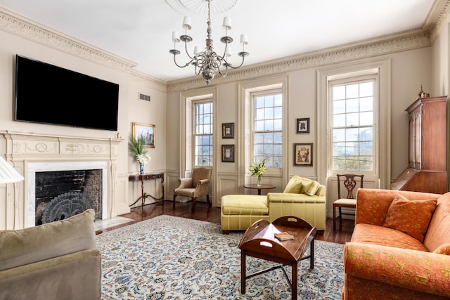 living room featuring dark wood-type flooring, plenty of natural light, ornamental molding, and an inviting chandelier