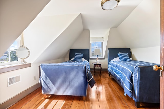 bedroom featuring hardwood / wood-style flooring, vaulted ceiling, and multiple windows