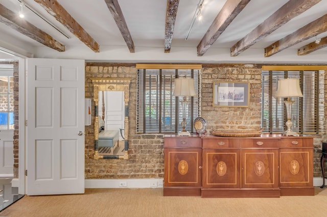 interior space featuring beamed ceiling, light colored carpet, plenty of natural light, and brick wall