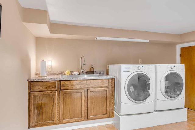 laundry area featuring washer and clothes dryer, cabinets, light tile patterned floors, and sink