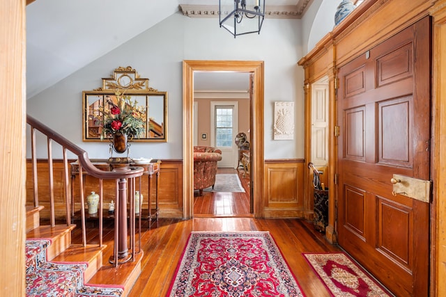 entrance foyer with hardwood / wood-style flooring, vaulted ceiling, and ornamental molding