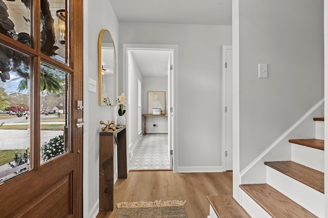 foyer featuring a wealth of natural light, light wood-type flooring, baseboards, and stairs