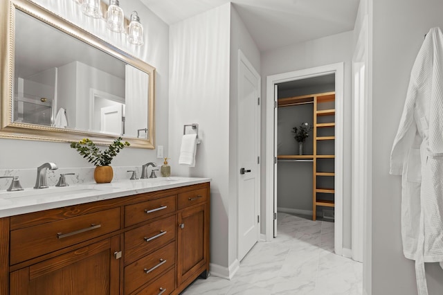 full bath featuring a sink, a walk in closet, marble finish floor, and double vanity