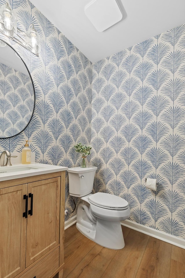 bathroom featuring wallpapered walls, toilet, and wood finished floors