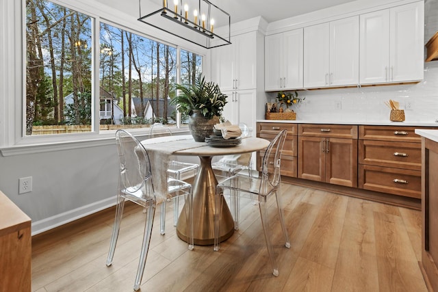 dining space featuring baseboards, an inviting chandelier, and light wood-style flooring