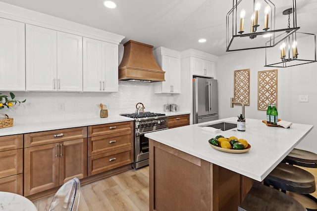 kitchen with high end appliances, custom exhaust hood, a sink, light countertops, and backsplash