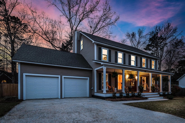 view of front facade with a porch, fence, concrete driveway, a shingled roof, and a garage