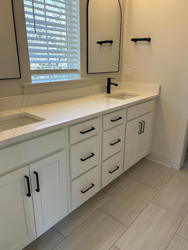 full bath featuring a sink, baseboards, and double vanity